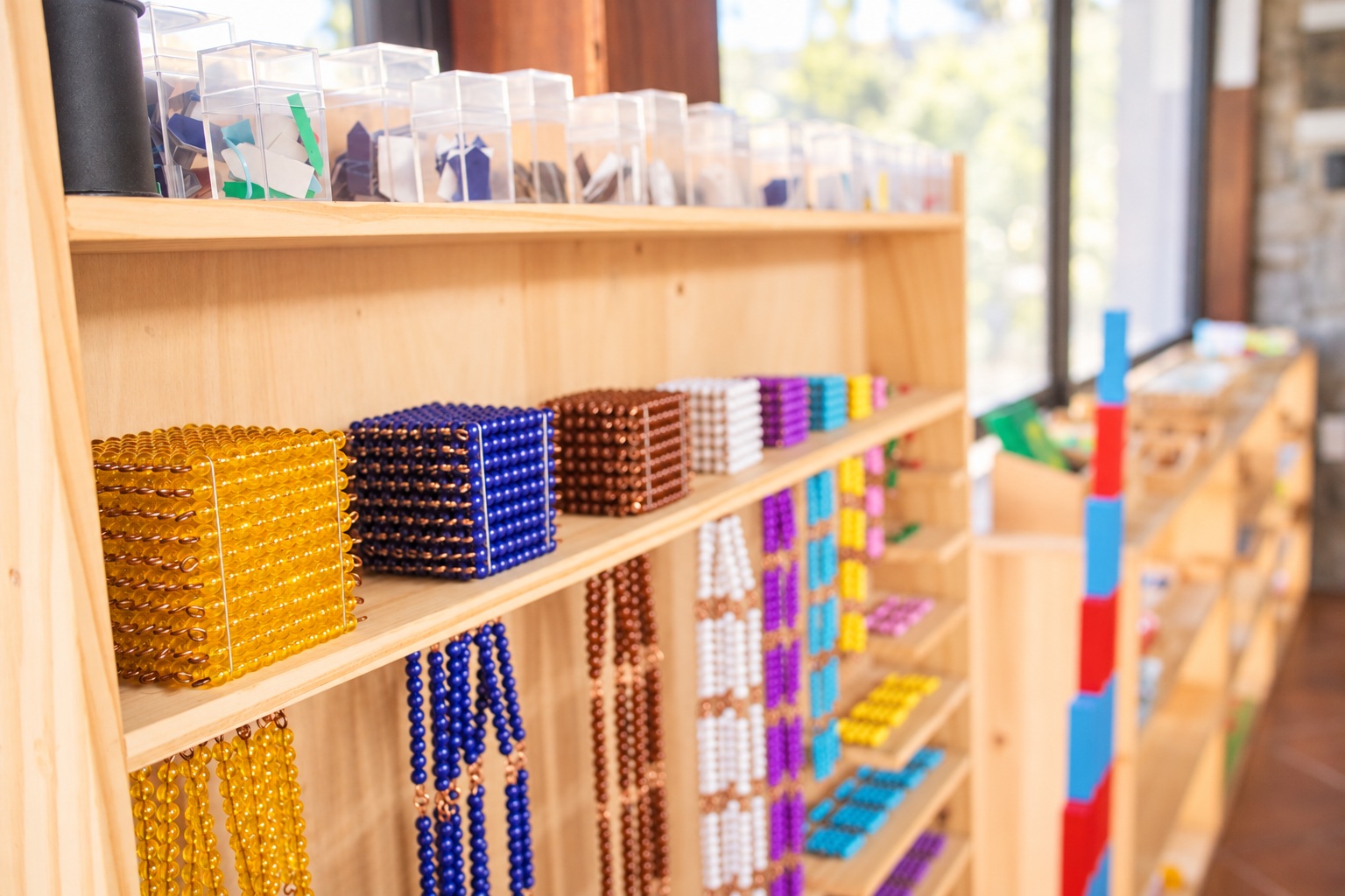 Materiales Montessori de matemática organizados en un estante de madera